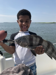 A happy young man Cooper Glinski with a chunky black drum.