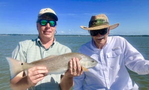Jim & Jean fishing on a windy day. Jim is holding a nice red.
